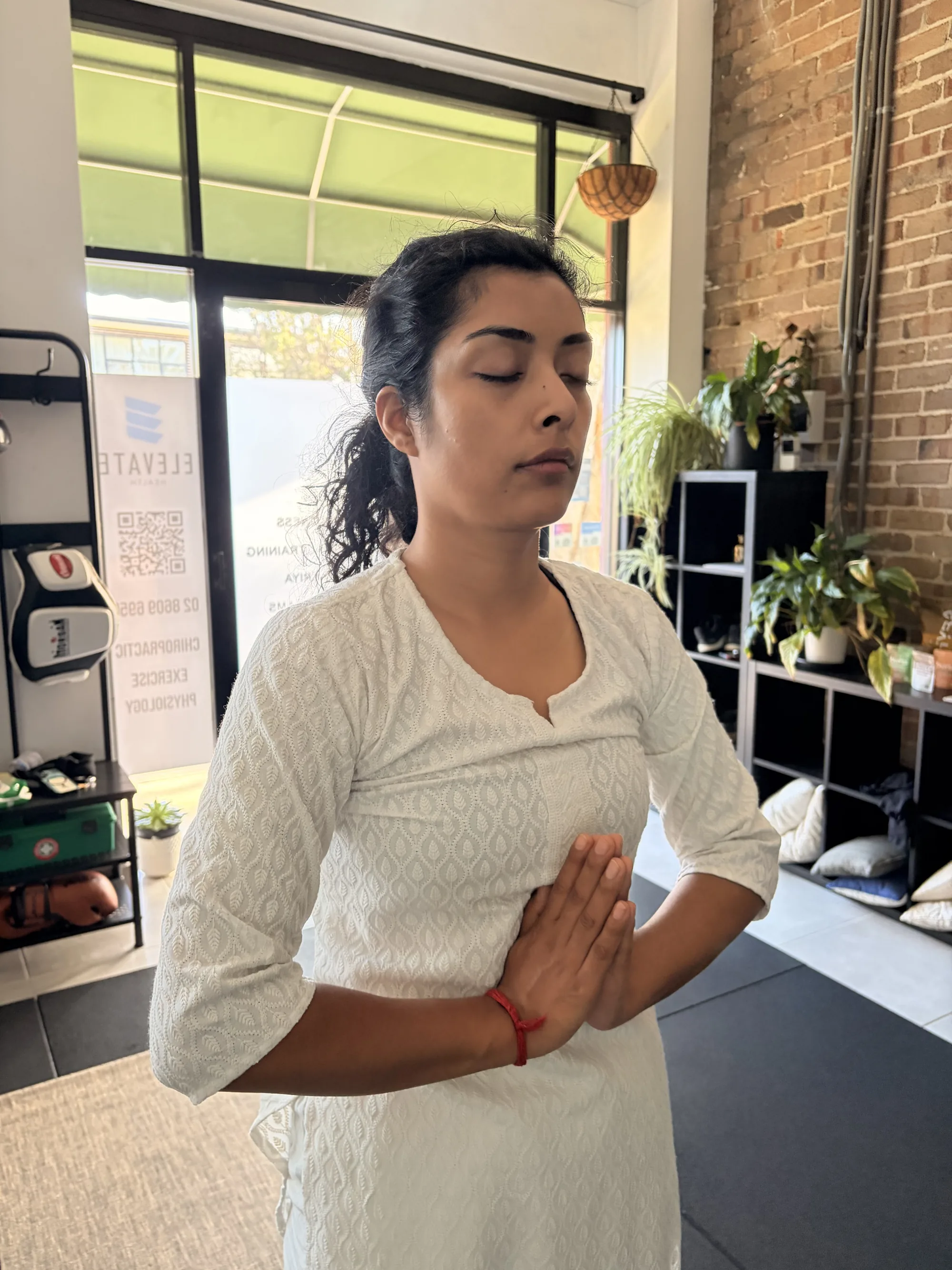Student in a standing prayer pose during a yoga class at the Adiyoga studio in Earlwood, Sydney